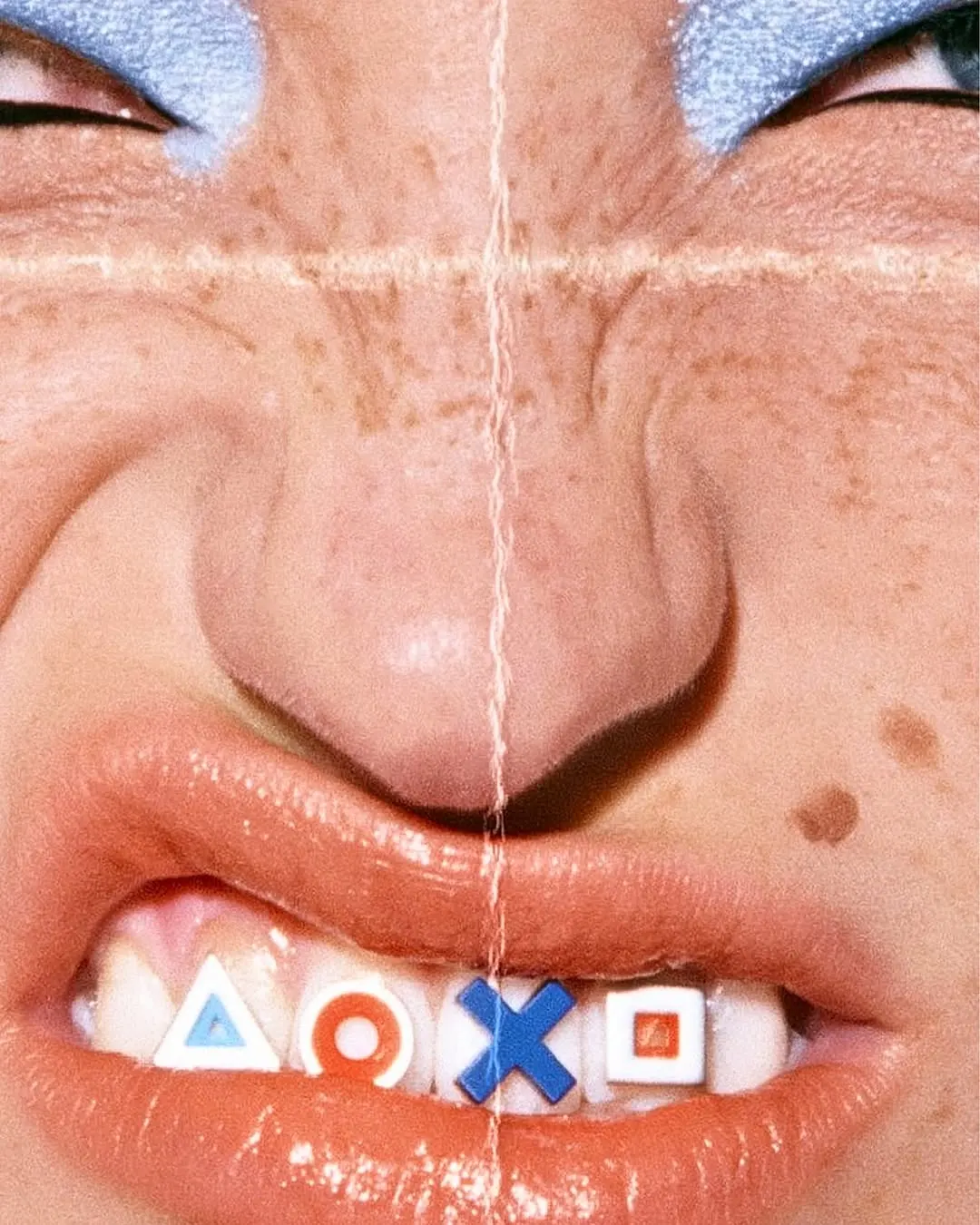 Close-up of a grimacing face with a strip of controller-button stickers