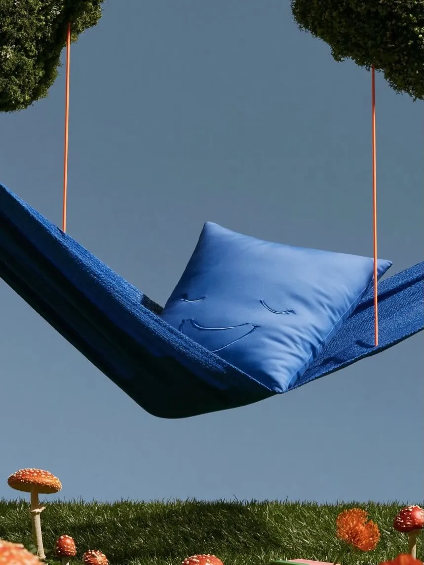 A blue cushioned bench hanging from ropes in an overgrown garden